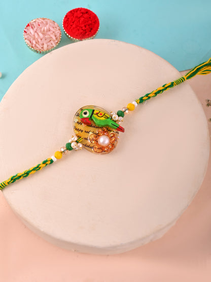 A Rakhi with a colorful parrot motif, featuring beads and a yellow-green thread.