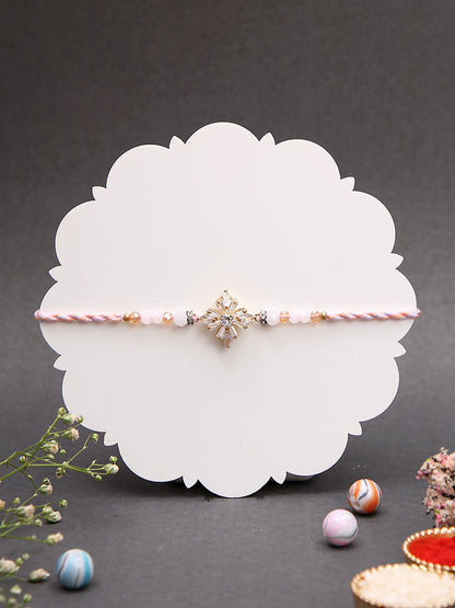 A minimalistic yet elegant Rakhi featuring a floral or star-shaped central piece with pastel