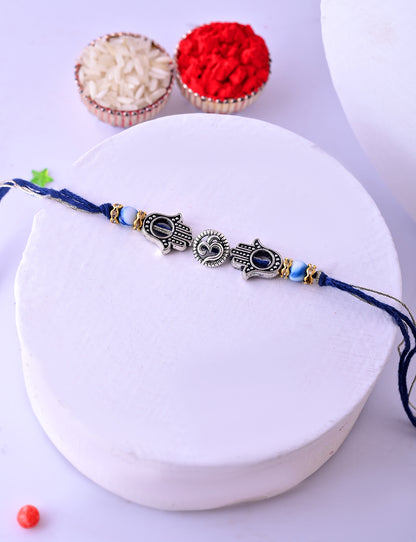 A Rakhi with double Hamsa hands and a central heart sun motif, with silver and blue accents.