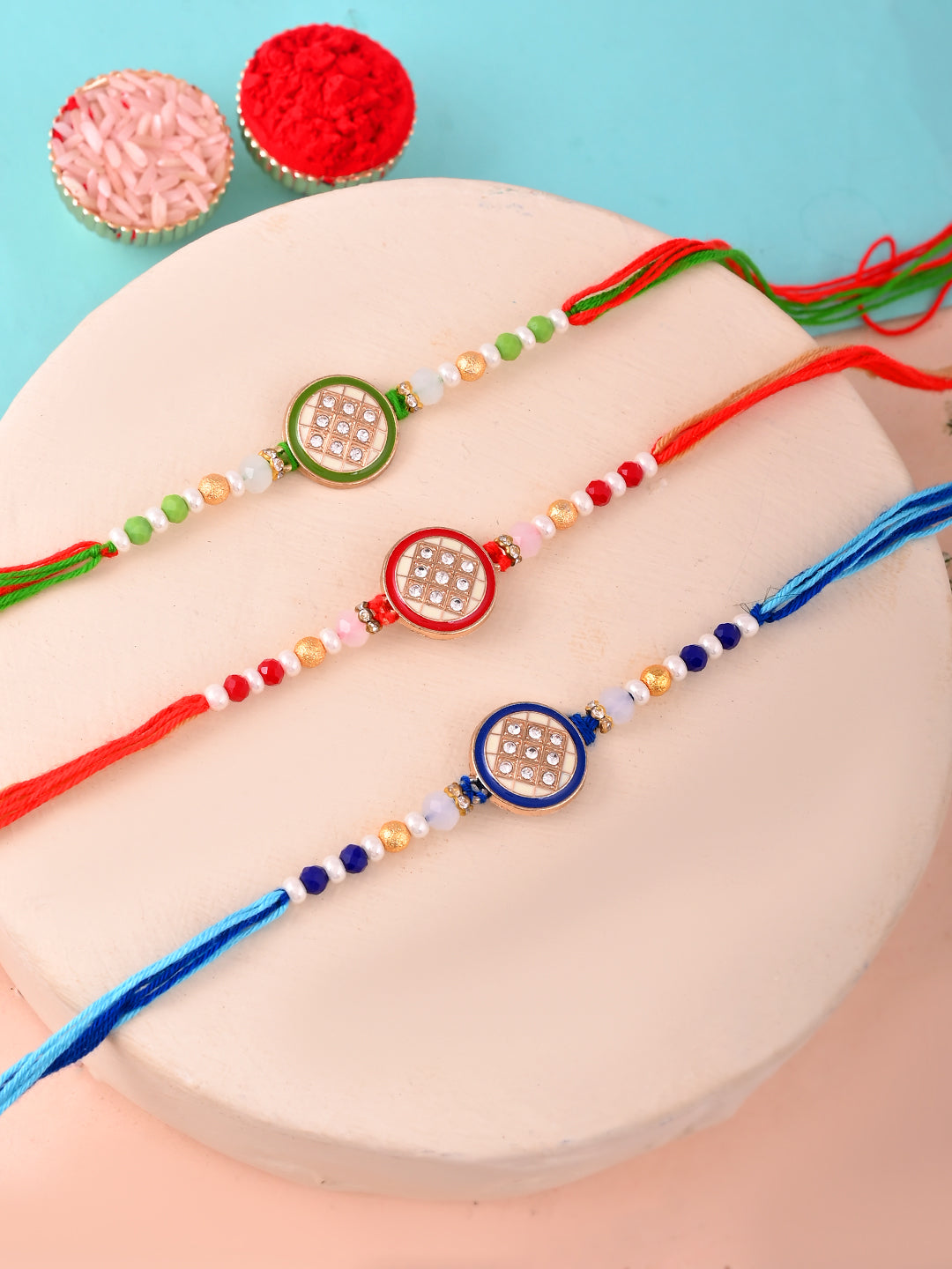 Trio of stone-studded Rakhis in green, red, and blue.